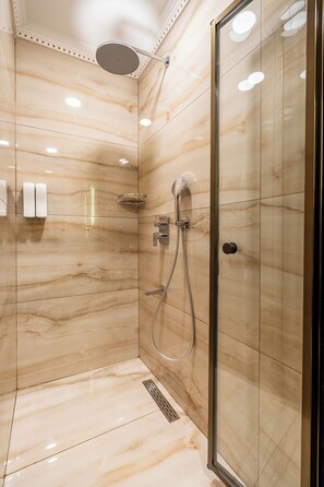 A modern shower with a glass door, marble walls, and a handheld showerhead. - Hanchi BY Ottoman Suites (İstanbul)