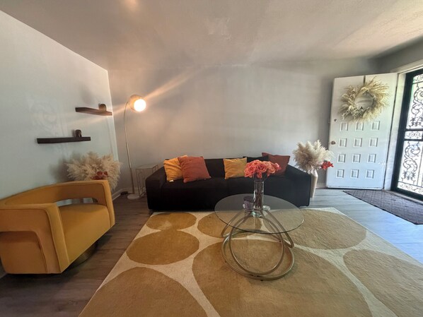 Una sala de estar con un sofá, una mesa de centro, una lámpara de pie y una puerta decorada con un adorno.