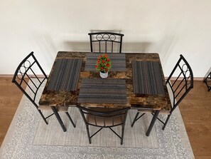 A dining table with a central vase, surrounded by chairs, on a patterned rug. - Cozy 1 bedroom apartment in Kileleshwa (PQCM+HQH, Nairobi)