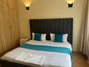 A hotel room with a bed, nightstand, and wardrobe. - Cozy 1 bedroom apartment in Kileleshwa (PQCM+HQH, Nairobi)