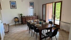A dining area with a table set for six, a wooden cabinet, and a door leading outside. - House 10 minutes walk from the sea (Martigues)