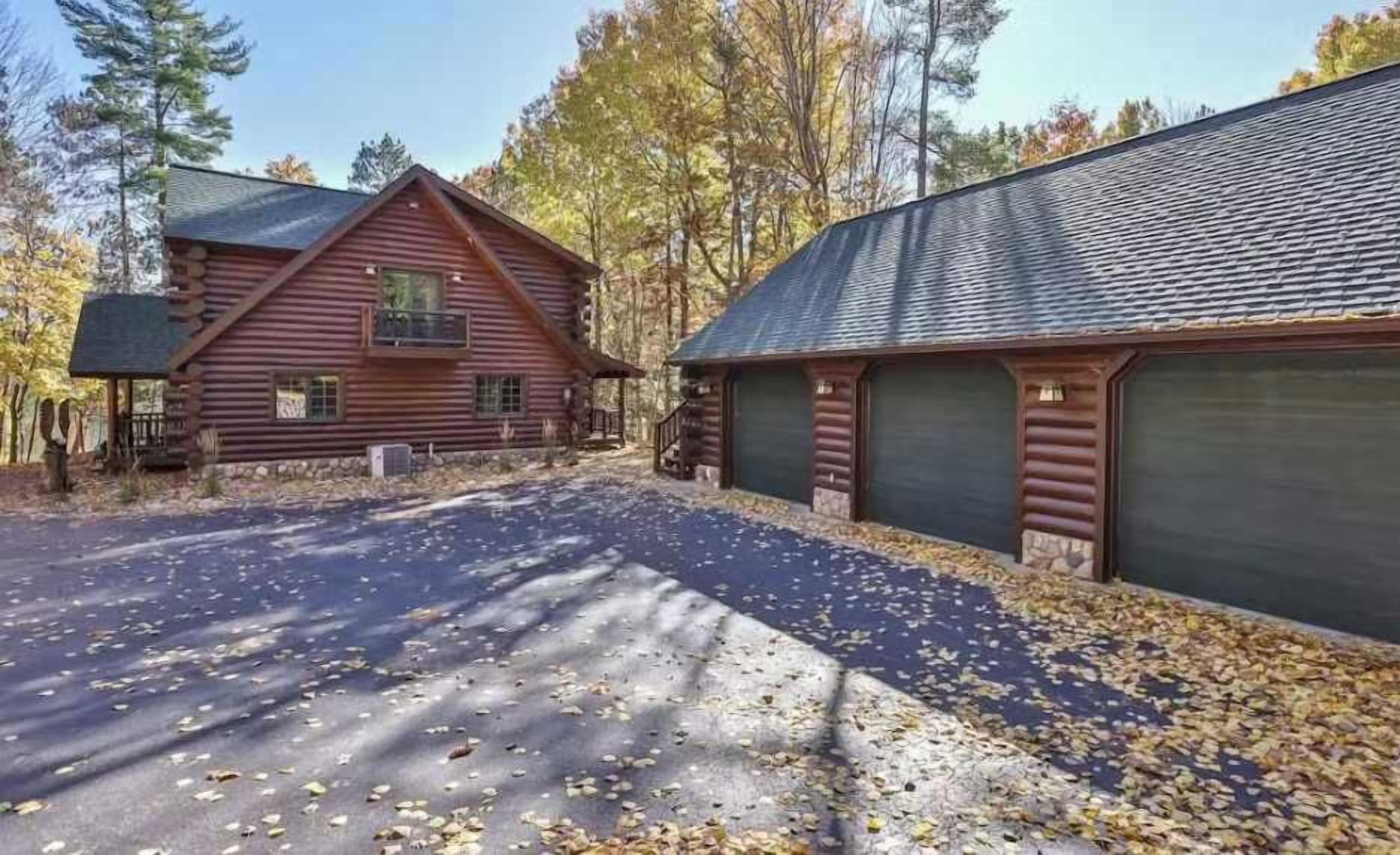 A log cabin with a covered driveway and a garage.