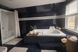 Casa de banho moderna com uma banheira grande, cabine de duche em vidro e uma janela com persianas.