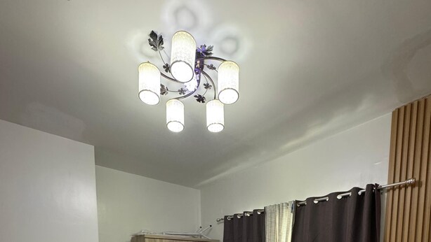 A bedroom with a bed, a wardrobe, a desk, and a ceiling light fixture.