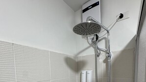 A shower with a handheld showerhead, a wall-mounted faucet, and a soap dispenser.