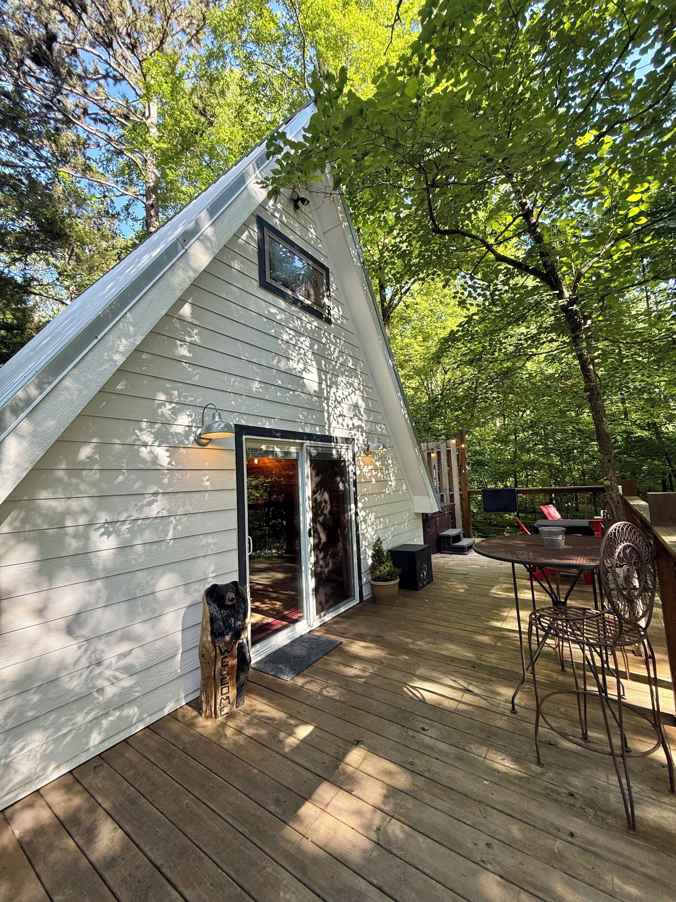Une maison avec un toit en pente, une terrasse et un espace patio aménagé avec du mobilier d’extérieur.
