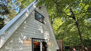 Une maison avec un toit en pente, une terrasse et un espace patio aménagé avec du mobilier d’extérieur.