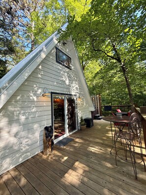 A house with a sloped roof, a deck, and a patio area with outdoor furniture.