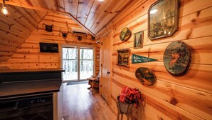 L’intérieur d’un chalet en bois comprend un coin cuisine, une table à manger et une cheminée.