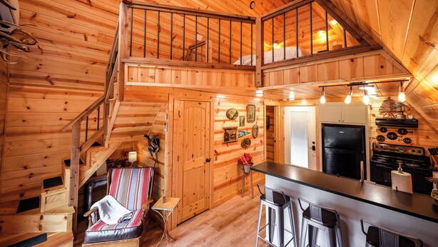 L’intérieur d’une cabane en bois comprend une chambre à coucher située en mezzanine, un coin repas et une cuisine.