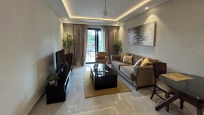 Una sala de estar moderna con sofá, mesa de centro, televisor y una mesa de comedor.