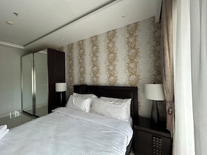 Una habitación de hotel con una cama grande, dos mesitas de noche, un espejo y un papel tapiz estampado.