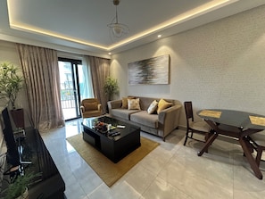 A modern living room with a sofa, coffee table, and dining table. - Lawrounds At Mirage  (Accra)