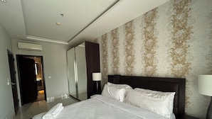 Habitación de hotel con una cama grande, un espejo, un armario y un baño visible a través de una puerta abierta.
