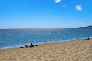Een zandstrand met kalm water en een heldere lucht.