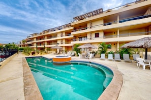 Un hotel con piscina, varios balcones y zonas de estar al aire libre.