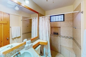 A bathroom with a shower, a sink with a mirror, and a towel rack. - Inviting Apartment Across From the Beach With Pool, Grill, Balcony & Golf Nearby (San José del Cabo)
