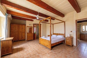 Une chambre à coucher avec un lit à baldaquin, des meubles en bois et un sol carrelé.