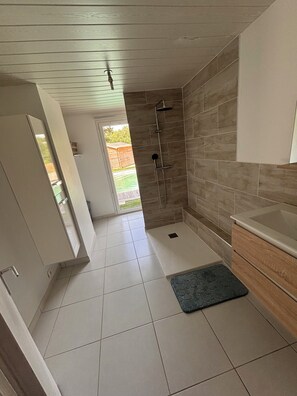 A modern bathroom with a shower, a sink, and a toilet. - Vrbo Property (Pornic)