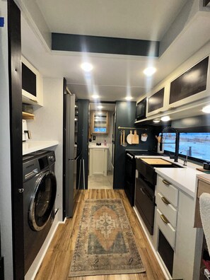 Una cocina compacta equipada con lavadora, refrigerador, microondas y pileta.