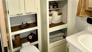 Een kleine badkamer met witte kastjes, een toilet en een wastafel.