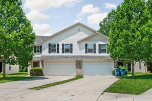 A two-story house with a garage, a driveway, and a well-maintained lawn. - Modern 4BR  - Townhouse Speedway 11min - Dwntwn 19min, Hot Tub (Indianpolis)