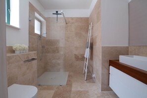 Une salle de bain moderne équipée d’une douche, de toilettes et d’un meuble-lavabo.