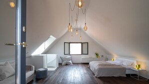Een moderne slaapkamer met een schuine kap, dakraam, een bed, nachtkastje en een stoel.