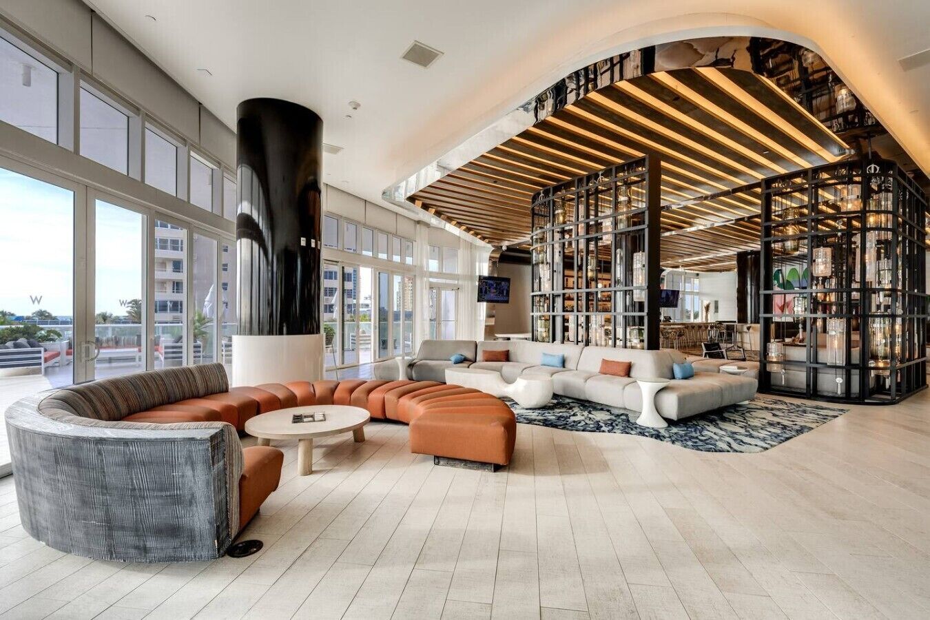 A spacious lobby with a curved seating area, a large black column, and a modern bookshelf.