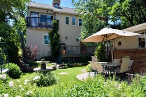 A residential building with a patio area featuring a table and chairs, a garden with a fountain, and a balcony. - Casa Artista Golden (Golden)