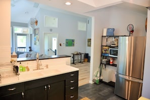 A modern kitchen with a stainless steel refrigerator, a sink with a faucet, and a countertop with various items.