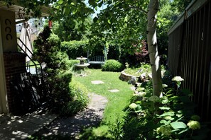 Un jardin avec un chemin de pierres, une balançoire et une fontaine.