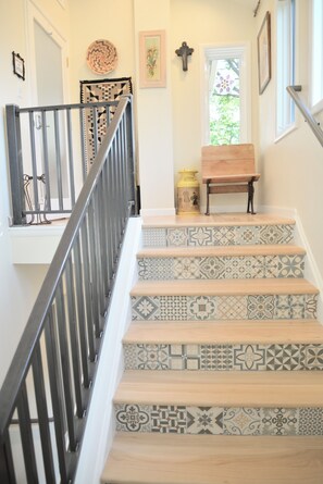 Un escalier orné de carreaux décoratifs, un banc en bois et une rambarde en métal.