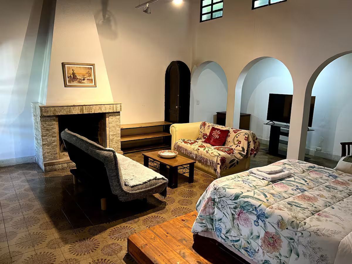 Una habitación con chimenea, un sofá, una cama y un televisor.
