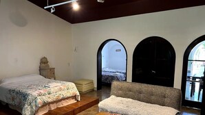 Una stanza con un letto, un divano, un piccolo tavolo e una panca. Sono presenti porte ad arco e si gode di una vista esterna.