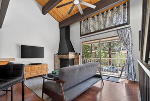 A living room with a fireplace, a sofa, a TV, and a wooden ceiling. - Tahoe Corner - 3 Minutes to Tahoe, 7 to Northstar - Pool, Pickleball, Fitness (Kings Beach)