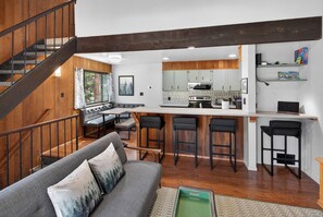 A modern kitchen with a central island, bar stools, and a dining area with a bench. - Tahoe Corner - 3 Minutes to Tahoe, 7 to Northstar - Pool, Pickleball, Fitness (Kings Beach)