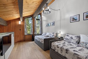 Een slaapkamer met twee bedden, een bureau en grote ramen.