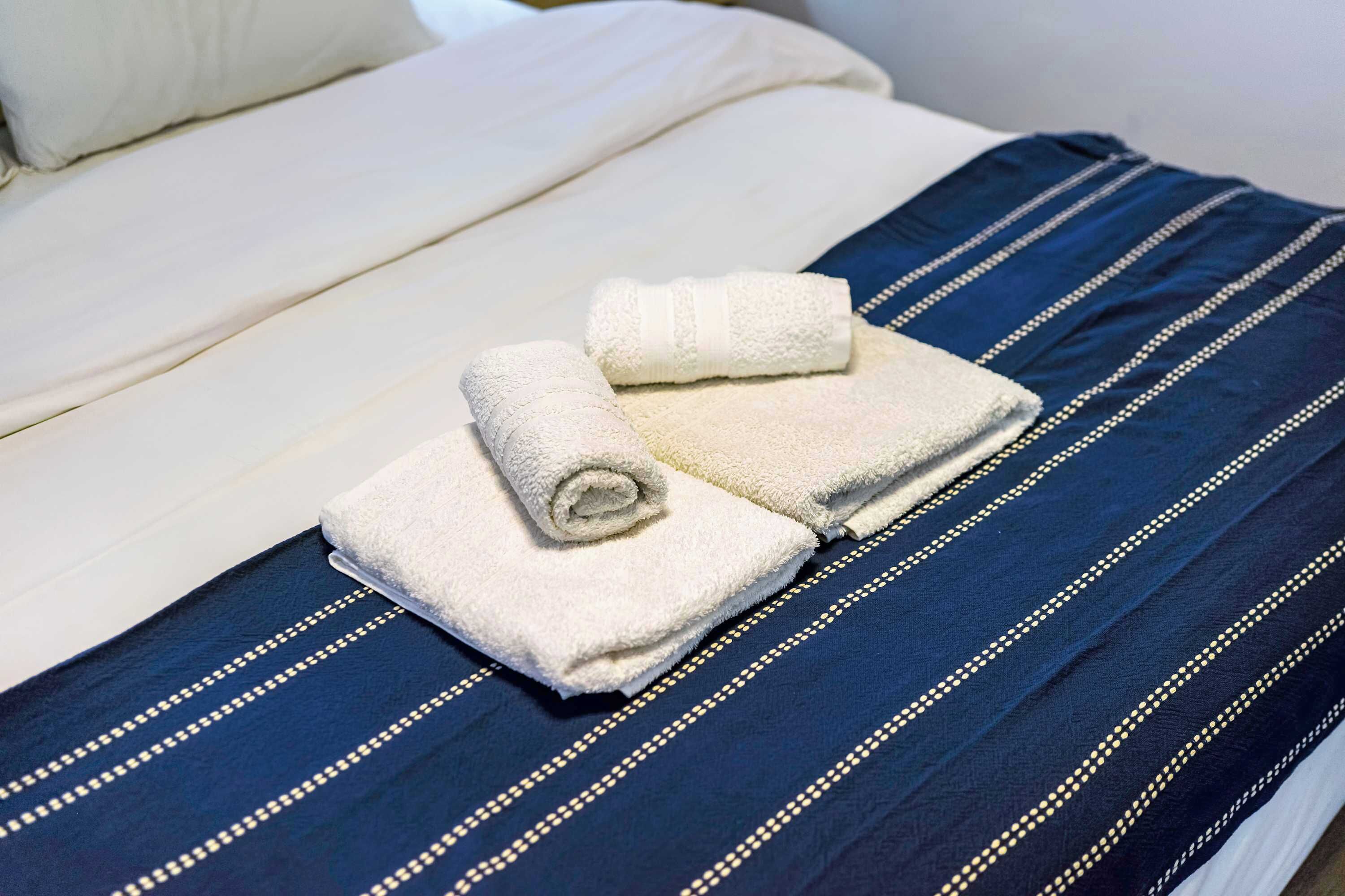 Een bed met een wit kussen en een deken met blauwe strepen.