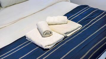 Una cama con una almohada blanca y una manta azul a rayas.