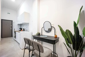 A modern kitchen with white cabinets, a built-in oven, and a coffee machine. - Modern Studio l King Bed & Work Corner (Vironas)