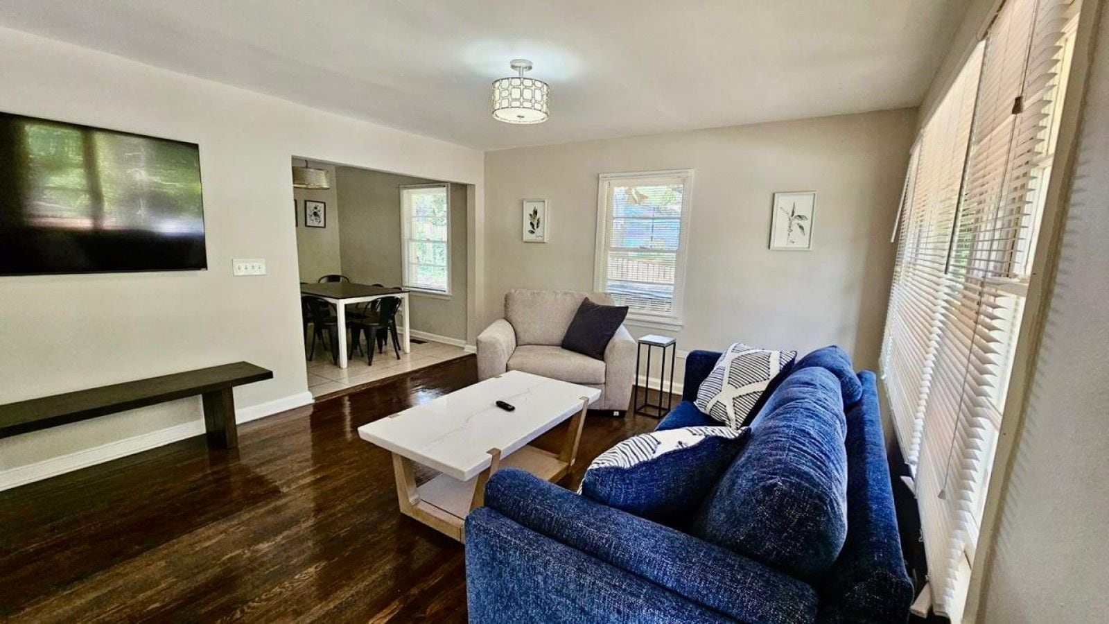 A living room with a sofa, coffee table, and a TV mounted on the wall.