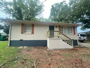 A single-story house with a front porch and a staircase leading to the entrance. - Decatur Executive Residential Stay | Sleeps 11 (Atlanta)