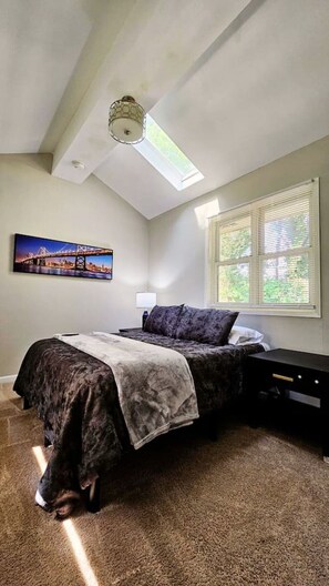 A bedroom with a bed, a skylight, a cityscape painting, and a window with blinds. - Decatur Executive Residential Stay | Sleeps 11 (Atlanta)