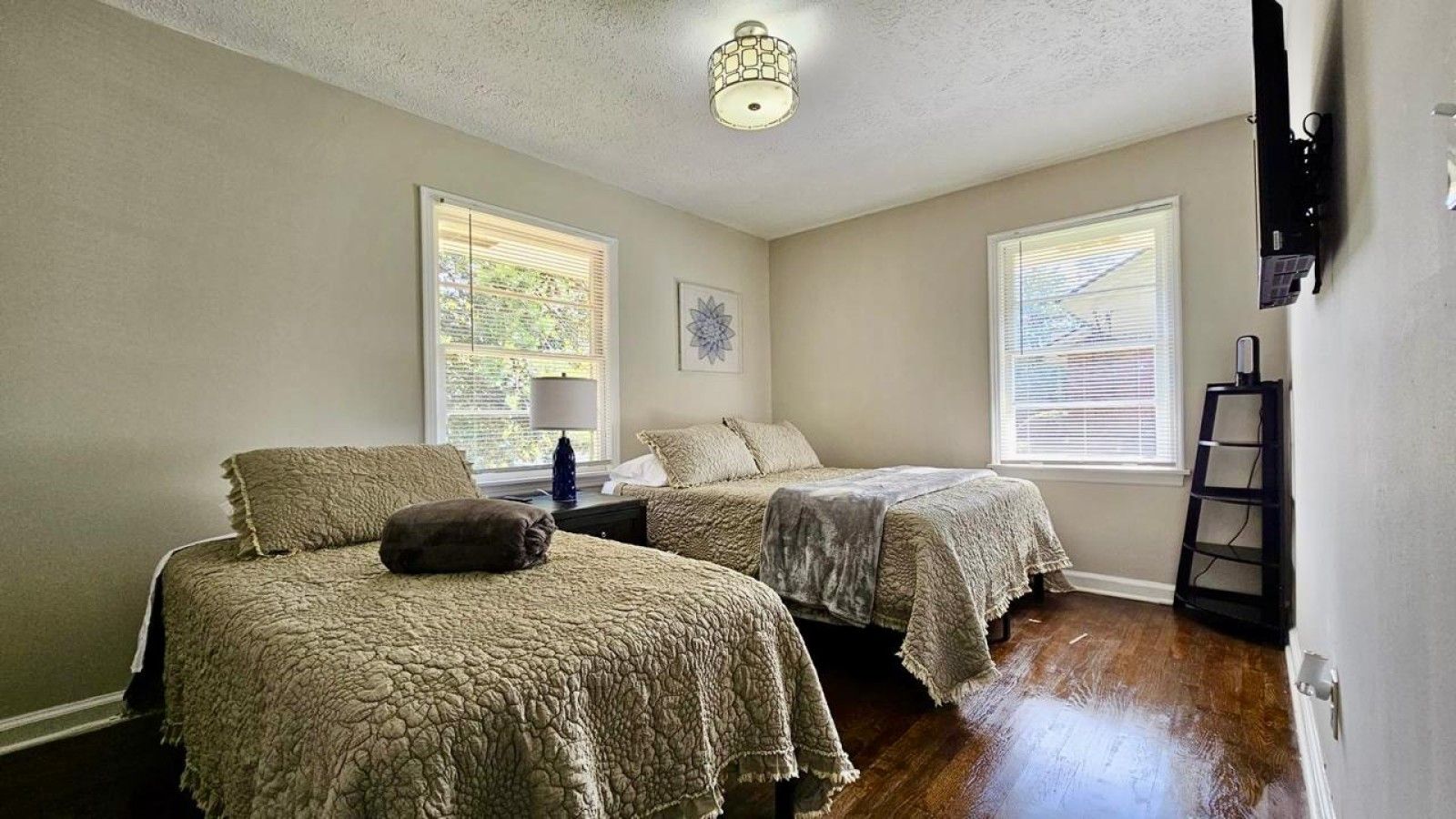 A bedroom with two beds, a nightstand, a lamp, and a ladder against the wall.