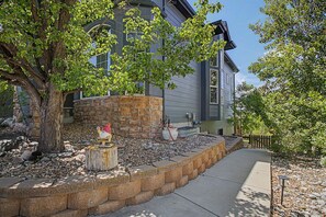 A house with a stone retaining wall, a tree, and a welcome sign. - Luxury Mountain View Retreat in Castle Pines (Castle Pines)