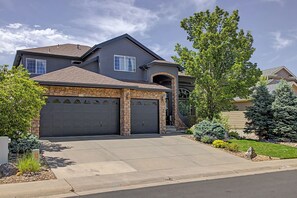 A two-story house with a stone facade, two garage doors, and a well-maintained front yard with various plants. - Luxury Mountain View Retreat in Castle Pines (Castle Pines)