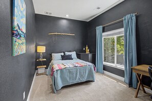 A bedroom with a bed, a nightstand, a lamp, a window with curtains, and a painting on the wall. - Luxury Mountain View Retreat in Castle Pines (Castle Pines)