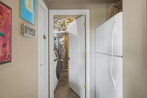 A hallway with a door leading to a laundry area, a thermostat, and a painting on the wall.