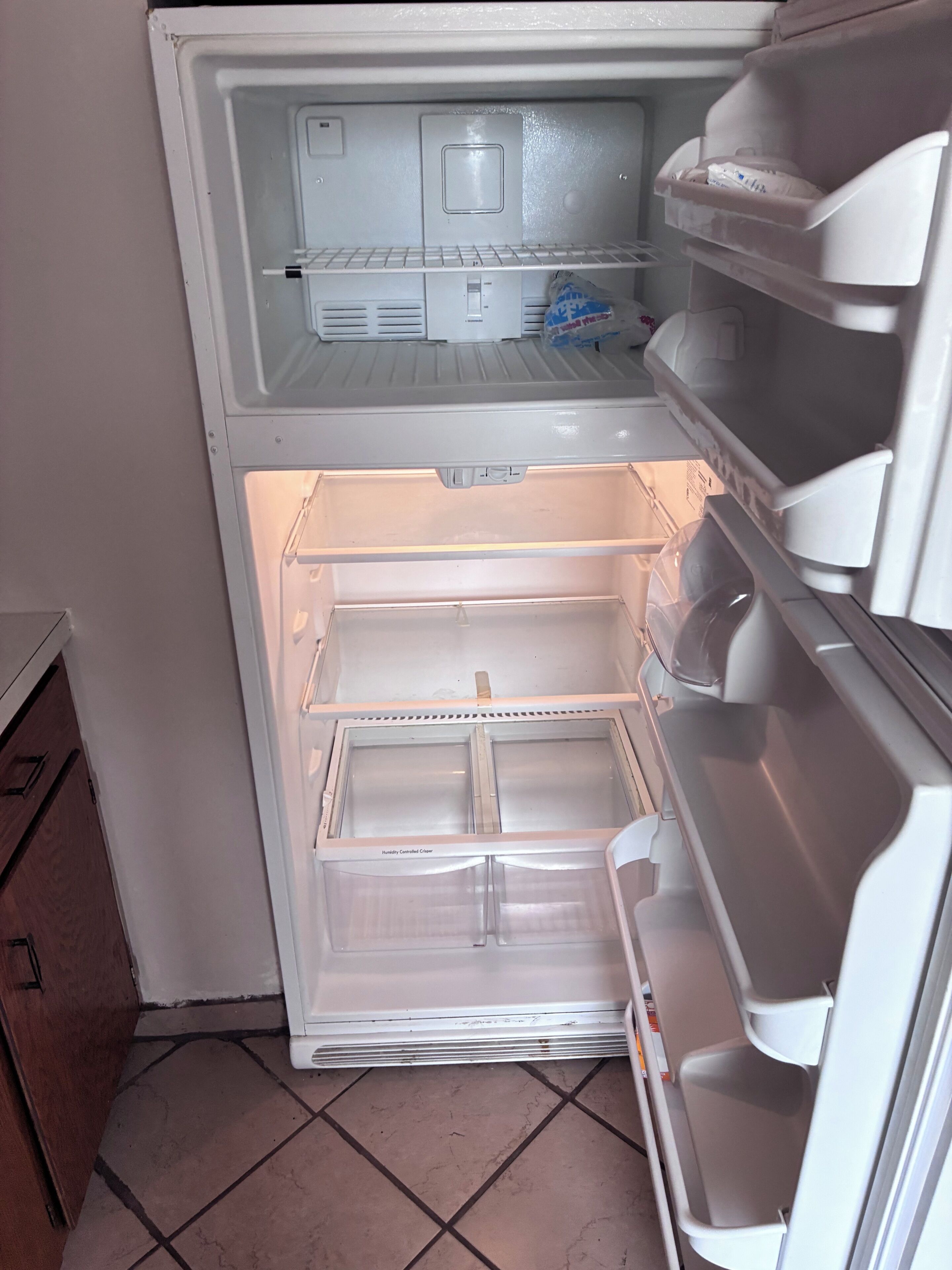 Un refrigerador abierto con varios estantes y un compartimento congelador.